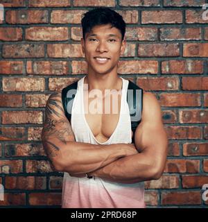 In der Turnhalle ist, wo Sie ihn finden. Ein gut gebauter Mann posiert gegen eine Backsteinmauer. Stockfoto