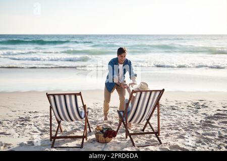 Lasst uns die Füße nass machen. Rückansicht eines Pärchens mittleren Alters, das auf den Liegen am Strand saß. Stockfoto