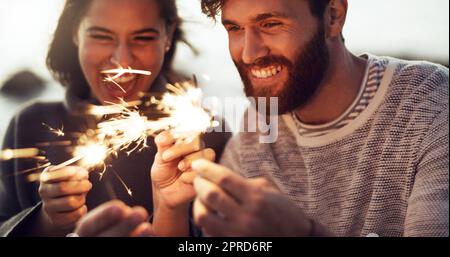 Ein junges Paar mit Wunderkerzen am Strand. Stockfoto