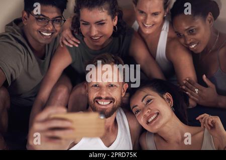 Gym Selfies sind immer die besten. Eine Gruppe junger Menschen, die Selfies nehmen, nachdem sie zusammen in einem Yoga-Kurs gearbeitet haben. Stockfoto