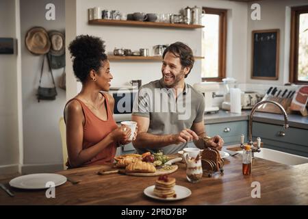 Es sieht aus wie ein schöner Tag. Ein liebevolles junges Paar beim Frühstück in ihrer Küche zu Hause. Stockfoto