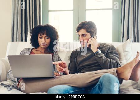 Wir bleiben immer auf dem Laufenden. Die ganze Aufnahme eines liebevollen jungen Paares, das auf einer Couch sitzt und zu Hause eine gute Zeit miteinander verbringt. Stockfoto