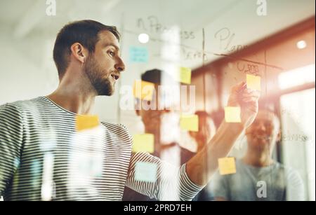 Teamleiter planen und schreiben auf Haftnotizen während des Brainstormings, Gesprächs oder des Austauschs von Visionen oder Ideen. Eine vielfältige Gruppe kreativer Geschäftsleute trifft sich zu einer Marktschulung in Neugründungen Stockfoto