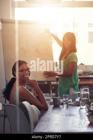 Weibliche Führungskraft präsentiert auf einem Whiteboard Ideen und Gedanken, während sie sich mit Kollegen in einem Vorstandssaal trifft. Portrait eines vielfältigen Teams, das Pläne und Strategien für ein Arbeitsprojekt diskutiert Stockfoto