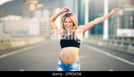 Eine attraktive junge Frau, die tagsüber im Freien einen Straßentanz vorführt. Stockfoto