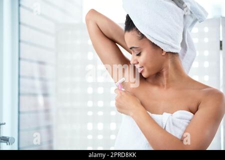 Lassen Sie uns über Achselpflege sprechen... eine attraktive junge Frau, die ihre Achselhöhlen mit einem Rasiermesser im Badezimmer rasieren kann. Stockfoto