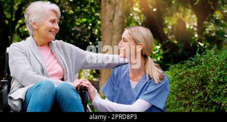 Ich bin dankbar, Sie zu haben. Eine fröhliche ältere Frau im Rollstuhl verbringt Zeit mit ihrer Tochter draußen in einem Park. Stockfoto