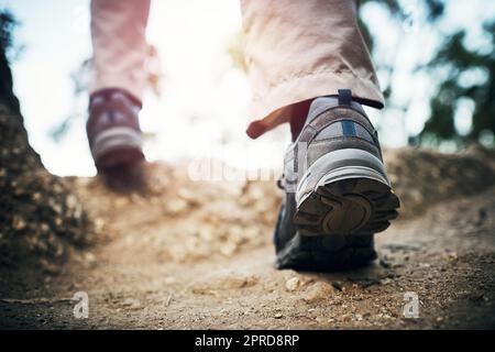 Bewegen Sie sich weiter, um die Spitze zu erreichen. Low-Angle-Aufnahme eines unkenntlichen Mannes, der tagsüber auf Felsen einen Berg hoch läuft. Stockfoto