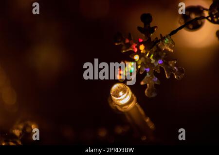 Bunte Weihnachtslichter als mehrfarbige Leuchtkette für ein frohes neues Jahr und Heiligabend als festliche Dekoration und Verzierung für Weihnachtsbaum im Adventszeit, die in dunkler heiliger Nacht hell leuchten Stockfoto