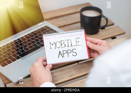 Textzeichen mit mobilen Apps. Kleine Programme für konzeptionelle Fotos sind für Telefone wie App Store oder App Store Geschäftsfrau konzipiert, die Notizblock mit wichtiger Nachricht auf dem Tisch mit Laptop in der Hand hat. Stockfoto