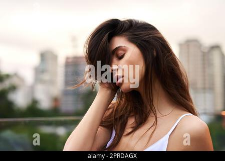 Eine attraktive junge Frau, die tagsüber auf einem Balkon im Freien steht. Stockfoto