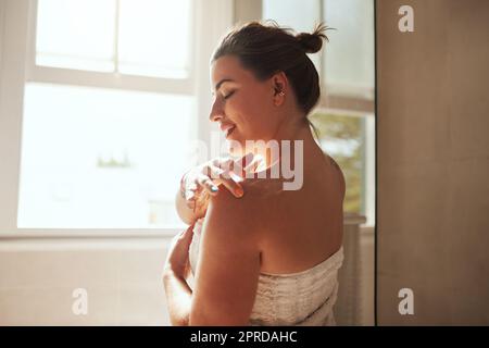 Unterschätzen Sie nie die Bedeutung von Feuchtigkeit. Eine attraktive junge Frau, die während ihrer morgendlichen Schönheitsroutine Feuchtigkeitspflege anwendet. Stockfoto