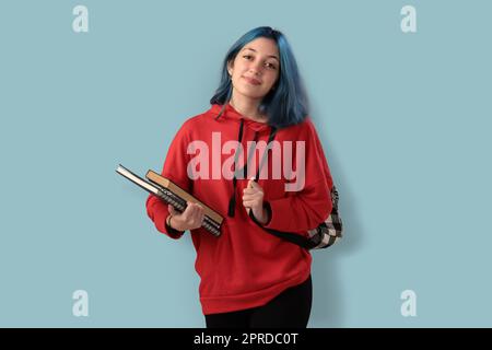 Süße junge Gilr-Schülerin mit blauen Haarbüchern und einem Rucksack Stockfoto