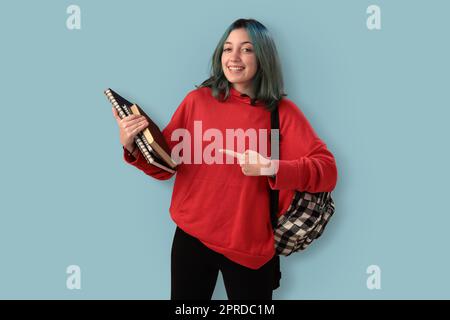 Süße junge Gilr-Schülerin mit blauen Haarbüchern und einem Rucksack Stockfoto