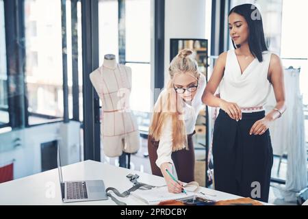 Keine Sorge, ich will sicherstellen, dass es passt Ihnen wie ein Handschuh. Eine erfolgreiche junge Modedesignerin in ihrer Werkstatt. Stockfoto