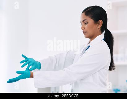 Ich denke, ich bin jetzt damit fertig. Eine attraktive junge Wissenschaftlerin, die ihre Handschuhe auszieht, während sie in einem Labor arbeitet. Stockfoto