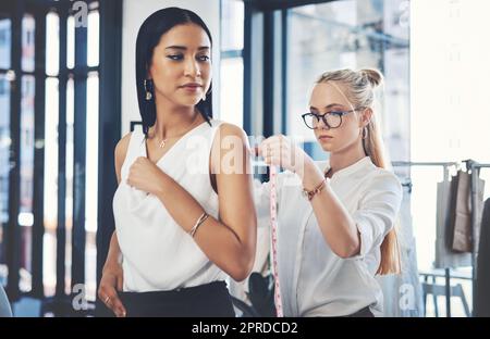 Meine Aufgabe ist es, jeden Frauentraum wahr werden zu lassen. Eine Modedesignerin, die ihre Kunden in ihrer Werkstatt misst. Stockfoto