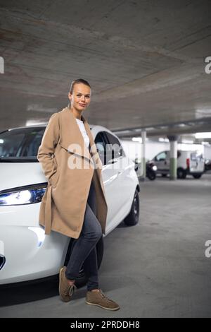 Tiefgarage (flaches, farbiges Bild des DOF) - eine junge Frau mit ihrem Auto in der Tiefgarage Stockfoto