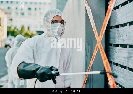 Medizinisches Fachpersonal bei Covid-Pandemie, desinfizierende und reinigende Bereich mit Desinfektionsmittel, Barriere- oder Vorsichtband und einer Gesichtsmaske. Notfallmediziner im Gefahrstoffanzug bei Coronavirus-Krise Stockfoto