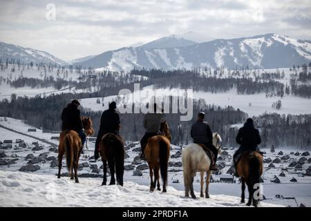 (230427) -- HEMU, 27. April 2023 (Xinhua) -- Suka (C) und Mitglieder eines Pferdeteams blicken über das Dorf Hemu auf einer Plattform in Kanas, der Autonomen Region Xinjiang Uygur im Nordwesten Chinas, 30. März 2023. HEMU Village liegt am malerischen Ort Kanas am Ausgangspunkt der G219 National Highway. Suka, die Parteisekretärin des Dorfes, führt die Einheimischen auf dem Weg zur ländlichen Neubelebung. Der Beitritt zum Pferdeteam ist eine wichtige Einnahmequelle für die Dorfbewohner. Jedes Mitglied kann zwei Pferde zum Team bringen, um den Service für Touristen bereitzustellen. Zurzeit haben 68 der Teammitglieder mit den Schultern gezuckt Stockfoto