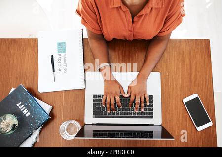 Lassen Sie uns dann an die Arbeit gehen. Die Aufnahme einer nicht erkennbaren Geschäftsfrau, die in einem Büro an einem Laptop arbeitet. Stockfoto