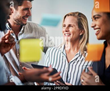 Sie planen gemeinsam. Gemeinsam gelingt es ihnen. Eine Gruppe von Geschäftskollegen, die in ihrem Büro auf einem Glaswischbrett Brainstorming durchführen. Stockfoto