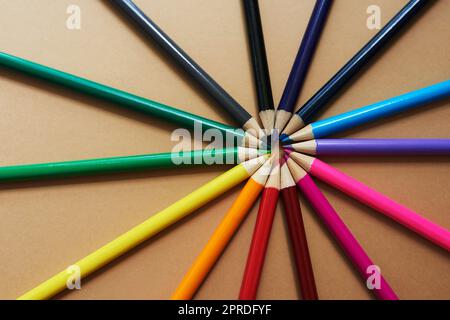 Leben Sie Ihr Leben in voller Farbe. Studioaufnahme von verschiedenen Buntstiften vor braunem Hintergrund. Stockfoto