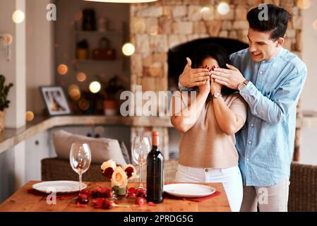 Ich habe etwas Besonderes für Sie geplant. Ein Mann überrascht seine Frau mit einem romantischen Abendessen zu Hause. Stockfoto