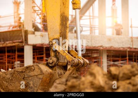 Schaufel des Baggerladers. Der Graber parkt auf der Baustelle. Bulldozer auf unscharfem Gebäude im Bau und Arbeiter. Erdbewegungsmaschine. Schmutzeimer des Grabers. Erdbewegungsmaschine. Ausgrabungsfahrzeug. Stockfoto