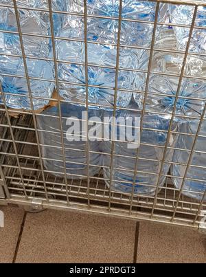 Lagerung und Transport von großen Plastikflaschen für sauberes Trinkwasser in einem Behälter mit Metallrost, Nahaufnahme Stockfoto