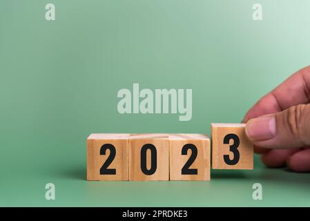 Mann Hand hält Holzwürfel Text 2023 Zielstrategie Geschäftskonzept auf grünem Hintergrund. Stockfoto