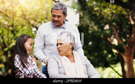 Sie hat immer interessante Geschichten zu erzählen. Ein entzückendes kleines Mädchen, das einige Zeit mit ihren Großeltern im Park verbringt. Stockfoto