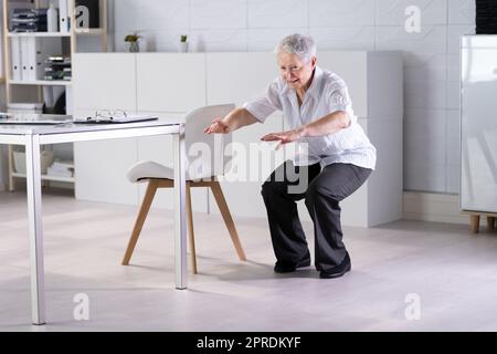 Eine Frau, Die Im Büro Yoga-Training Macht, Sitzt Auf Und Dehnt Sich Stockfoto