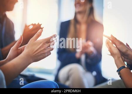 Lassen Sie uns eine Runde Applaus geben. Eine Gruppe von nicht erkennbaren Geschäftsleuten klatscht sich während eines Treffens bei der Arbeit in die Hände. Stockfoto