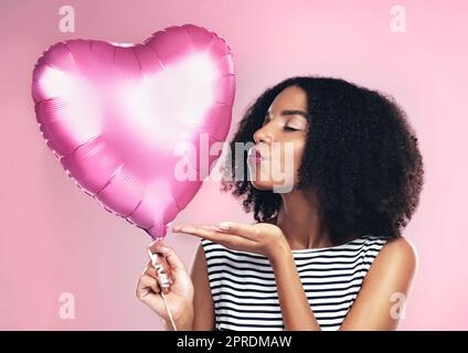 Senden Liebe Ihren Weg. Eine junge Frau hält einen herzförmigen Ballon. Stockfoto