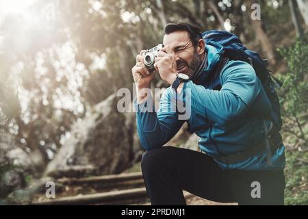 Eine saubere Aufnahme davon zu bekommen, ist ziemlich schwierig. Ein Mann mittleren Alters, der mit seiner Kamera in den Bergen fotografiert. Stockfoto