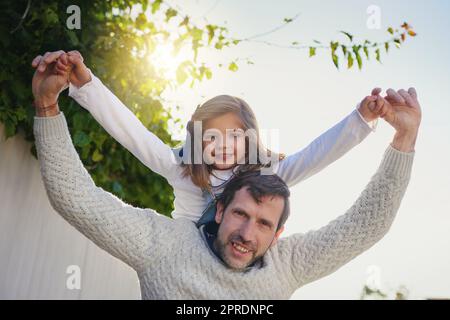 Shell immer mein kleines Mädchen. Ein glücklicher Vater und Tochter genießen eine Huckepack Fahrt in ihrem Hinterhof. Stockfoto