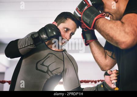 Halten Sie Ausschau nach den hinterhältigen Schlägen. Zwei junge Boxer stehen sich tagsüber in einem trainingssparenden Match in einem Boxring in einem Fitnessstudio gegenüber. Stockfoto