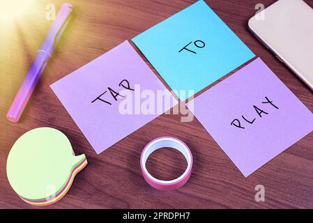 Schild mit der Anzeige „Tippen zum Abspielen“. Geschäftsidee Berühren Sie den Bildschirm, um ein Spiel oder eine andere wichtige Nachricht zu spielen, die auf drei „Notes on Desk“ mit Memos und Band geschrieben wurde. Stockfoto