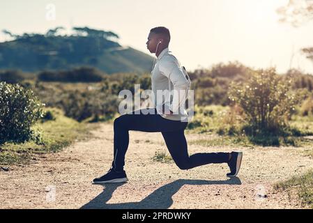 Konzentriert sich auf seine Fitness. Ganzkörperaufnahme eines hübschen jungen Mannes, der sich vor dem Training im Freien dehnt. Stockfoto