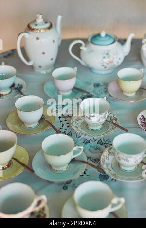 Der Tisch ist eingestellt, Zeit, um die Tee-Party zu beginnen. Teekannen und Teebecher auf einem Tisch bei einer Tee-Party im Inneren ausgelegt. Stockfoto