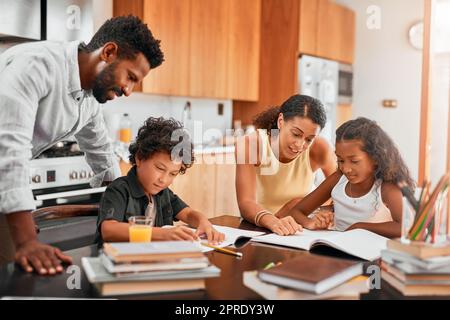 Spielen Sie eine aktive Rolle in Ihren Kindern Hausaufgaben. Eltern helfen ihren beiden Kindern bei ihren Hausaufgaben. Stockfoto