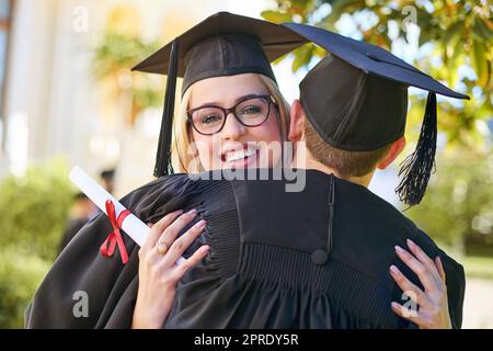 Der Tag der Abschlussfeier ist ein Tag zum Feiern. Ein junges Paar umarmt sich am Tag der Abschlussfeier. Stockfoto