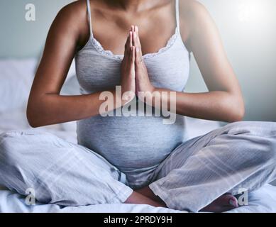 Yoga lehrt dich, ruhig zu bleiben. Eine Schwangerin macht Yoga in ihrem Schlafzimmer. Stockfoto