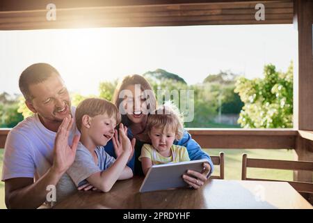 Eine Familie, die im Ausland einen Videoanruf auf einem digitalen Tablet macht. Stockfoto