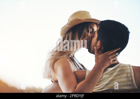 Ihre Küsse entsprechen dem Glück. Ein liebevolles junges Paar, das einen intimen Moment draußen auf ihrem Balkon teilt. Stockfoto