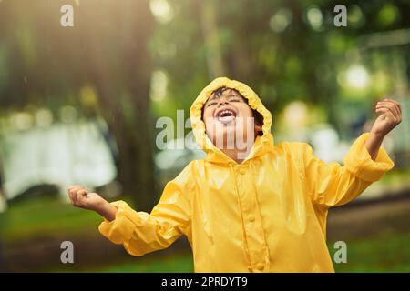 Einige Leute verstecken sich vor dem Regen, er umarmt ihn. Ein entzückender kleiner Junge im Regen draußen. Stockfoto