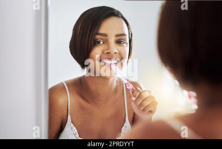 Ich muss sie glitzern und weiß halten. Porträt einer attraktiven jungen Frau, die sich im Badezimmer die Zähne putzt. Stockfoto