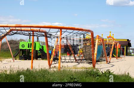 Moderner öffentlicher Spielplatz vor dem blauen Himmel. Ein farbenfroher Spiel- und Sportkomplex für Kinder ohne Menschen. Ausrüstung für Klettern und Angriff auf den Spielplatz. Stockfoto