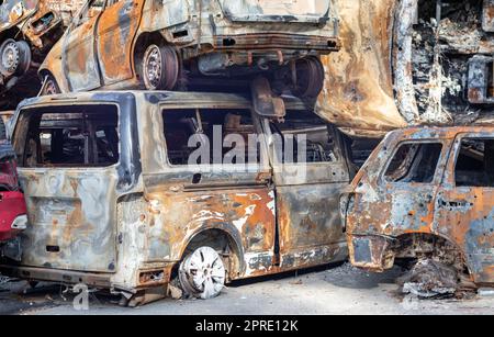 Rostige verbrannte Autos, die durch Raketenexplosionen zerstört wurden. Krieg in der Ukraine. Zerstörte Fahrzeuge von Zivilisten, die abfuhren, wurden aus der Kampfzone von Bucha und Irpin evakuiert. Autofriedhof. Stockfoto